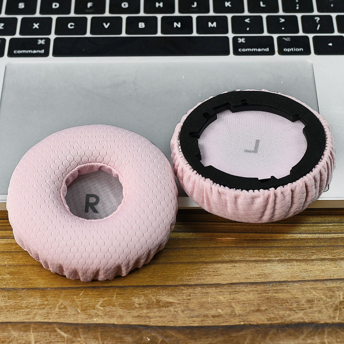 Dos almohadillas rosas para auriculares con marcas R y L en un portátil.