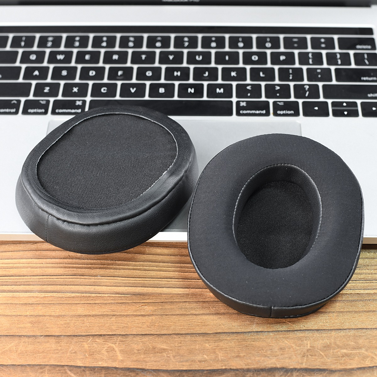 Dos almohadillas negras descansan sobre un teclado de portátil y madera.