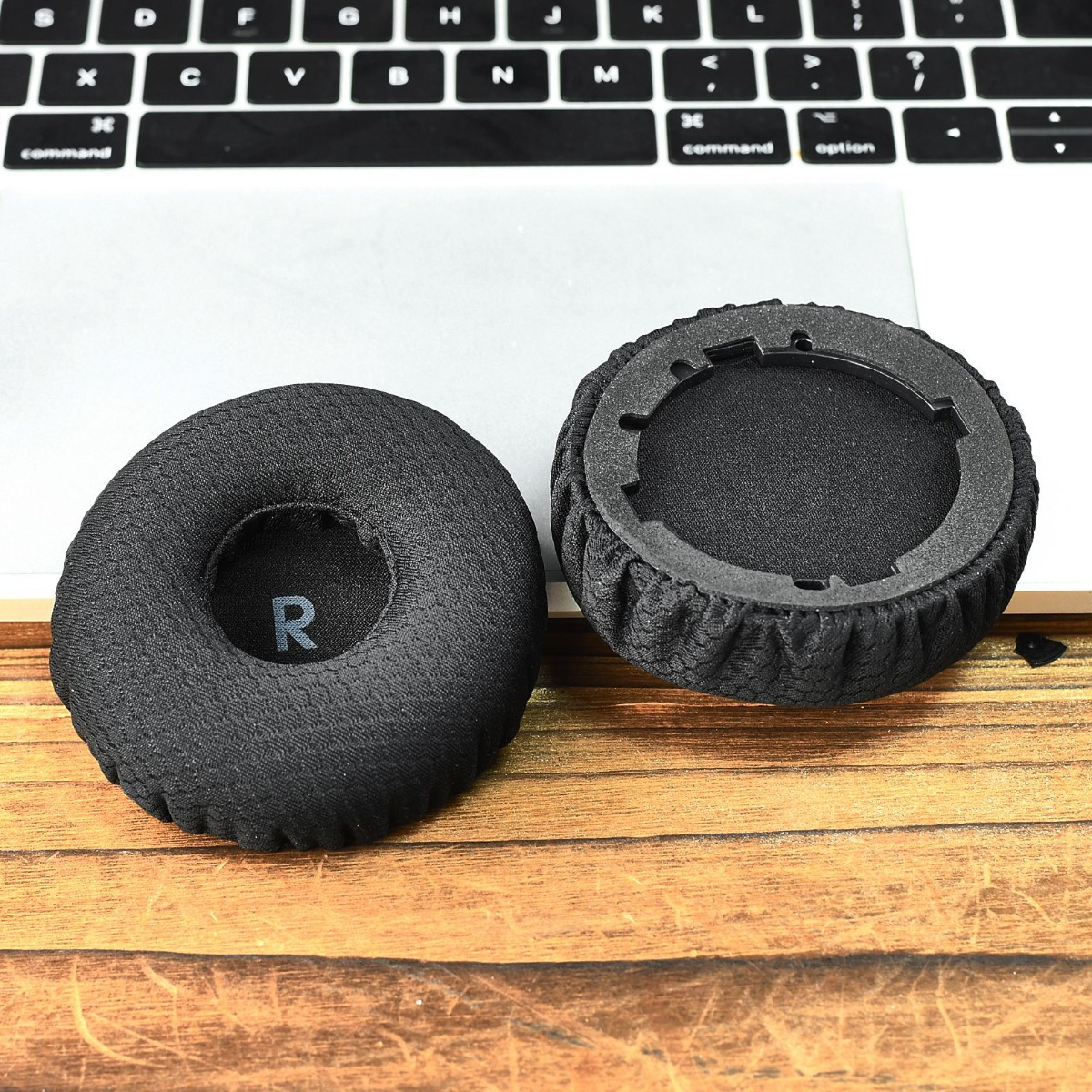 Dos almohadillas negras, una marcada "R", yacen sobre una superficie de madera.