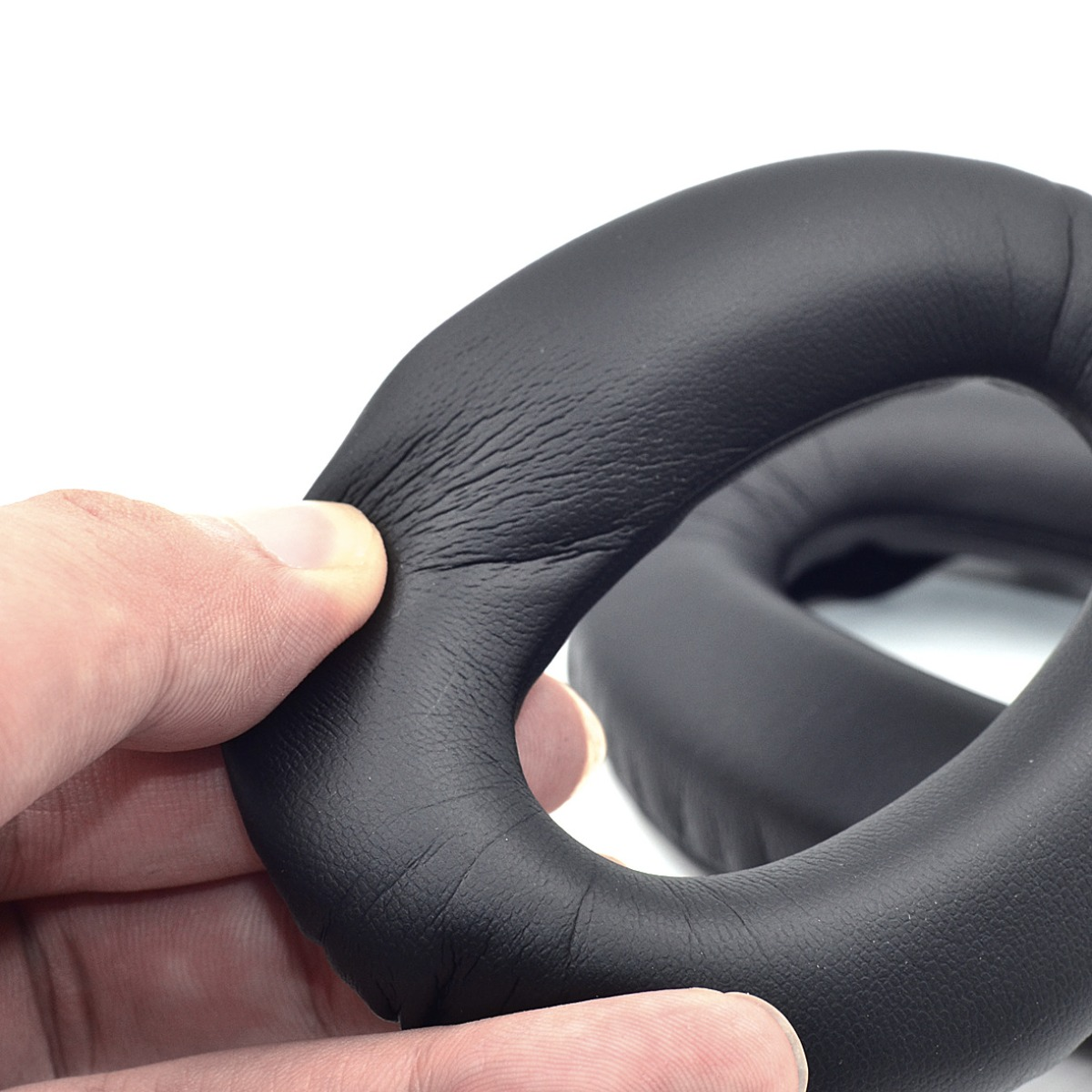 Mano presionando almohadilla negra similar al cuero para auriculares.