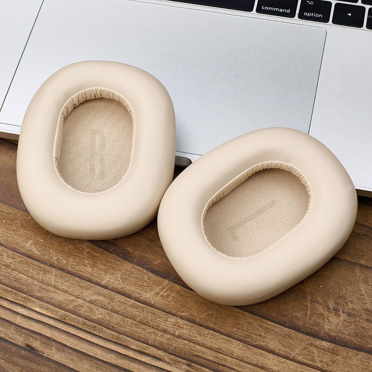 Dos almohadillas color crema descansan sobre una mesa de madera frente a un teclado.