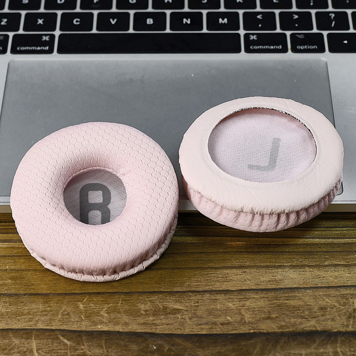 Dos almohadillas rosas para auriculares, marcadas L y R, sobre un teclado.
