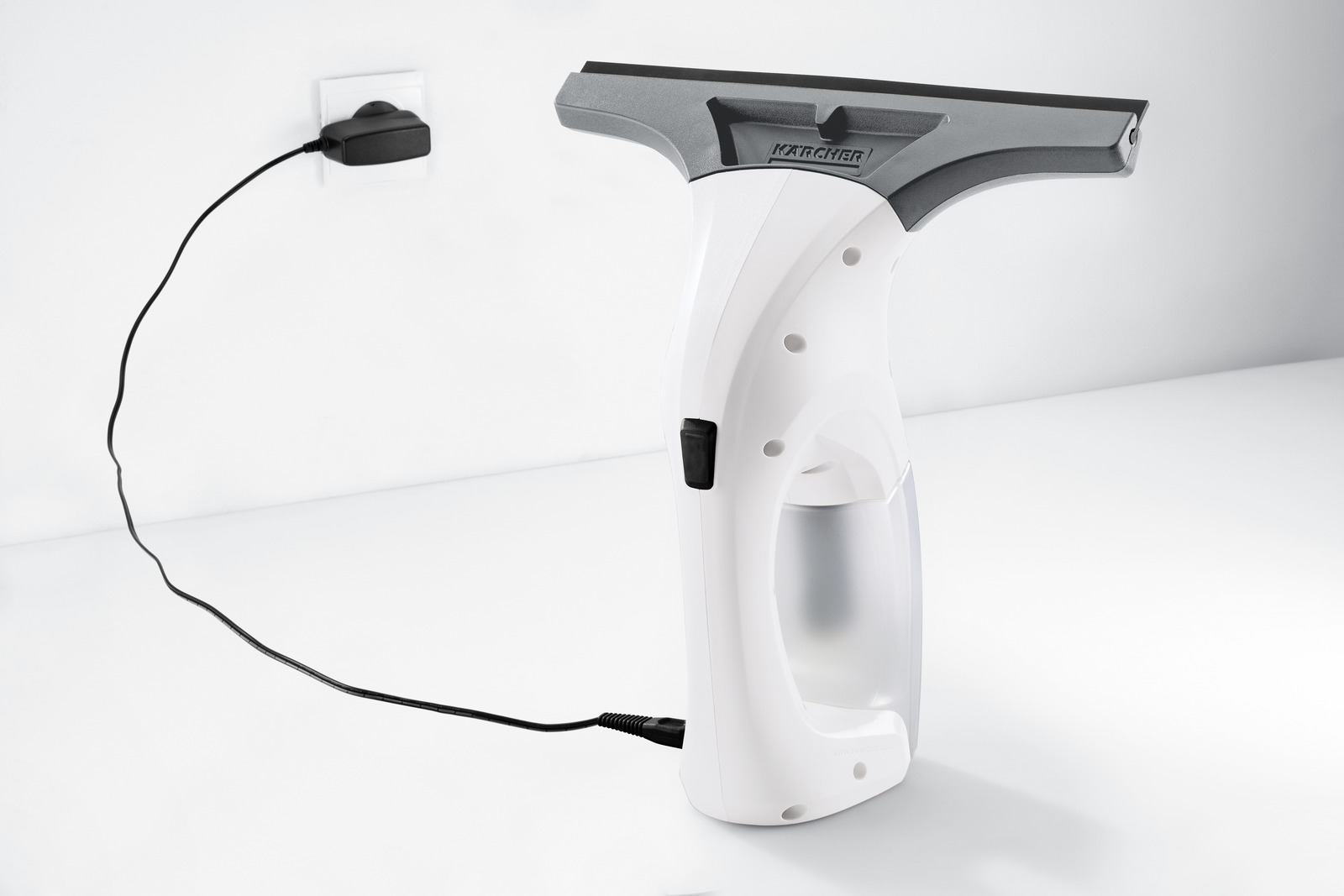 Biały czyścik do okien Kärcher z czarnym kablem jest podłączony do gniazdka.