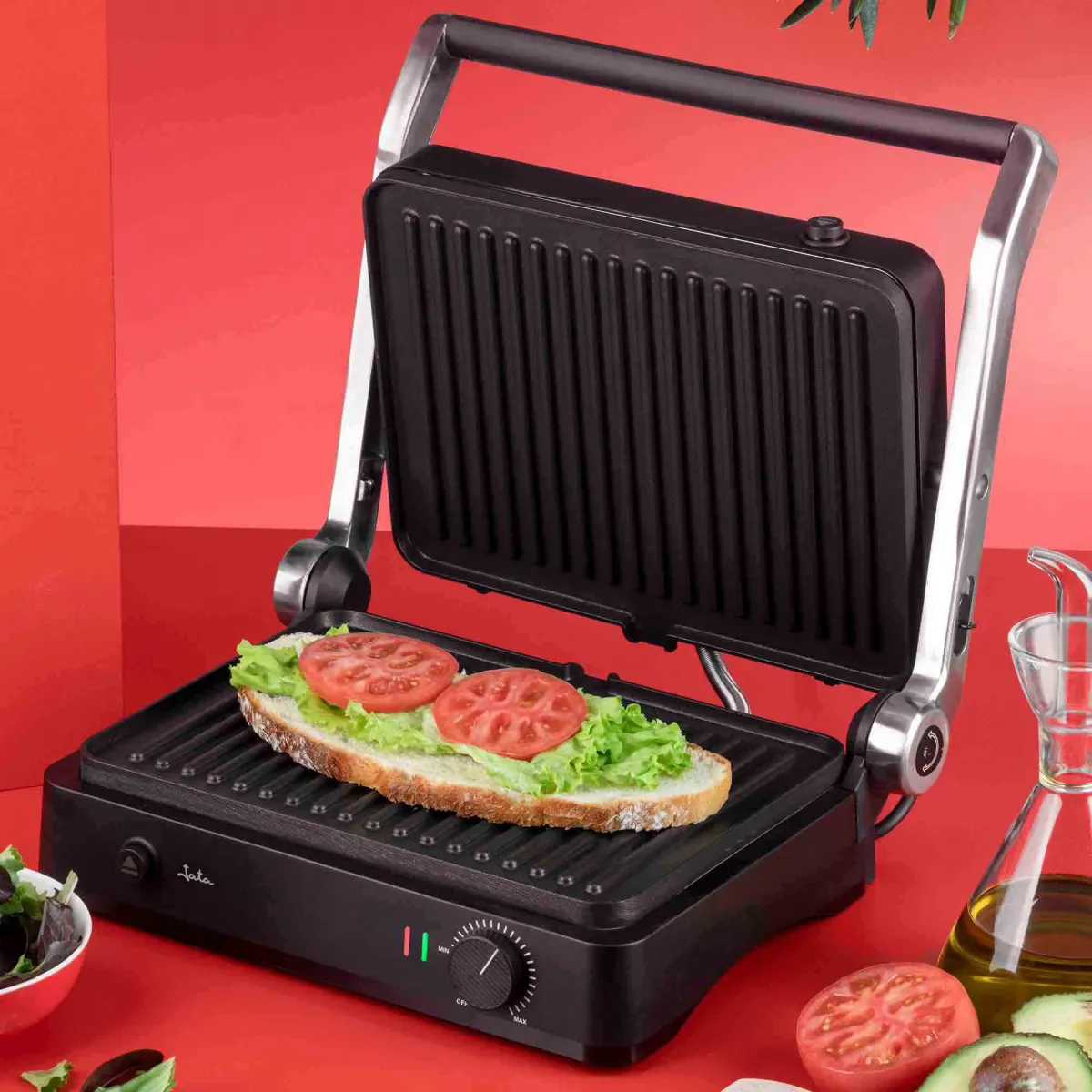 Una parrilla de contacto abierta con un sándwich de pan, lechuga y tomates.