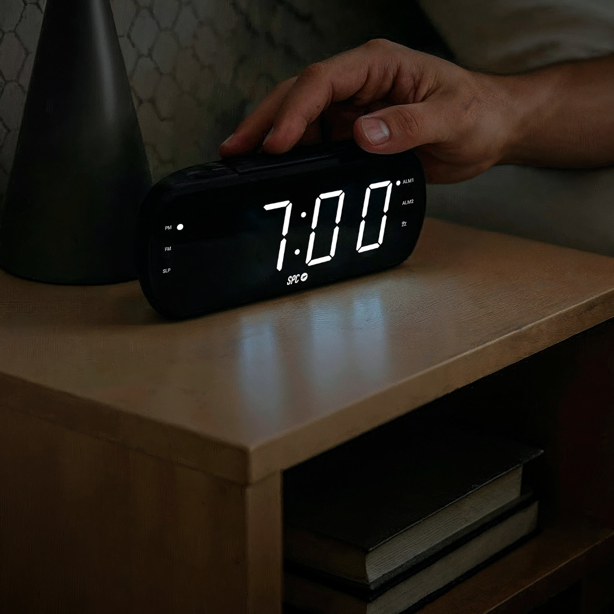 Una mano presiona un despertador digital que marca las 7:00.