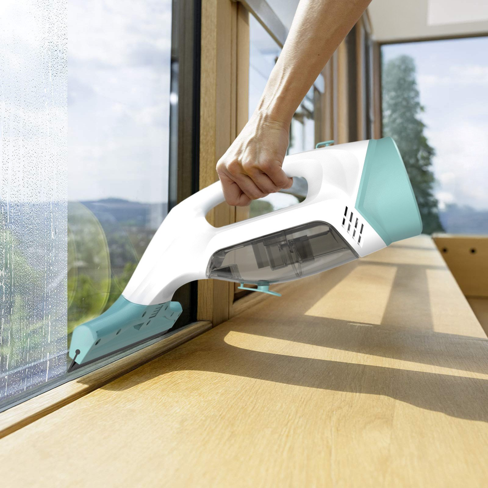 Eine Hand hält einen weißen Fensterreiniger mit türkisen Akzenten und reinigt ein Fenster.
