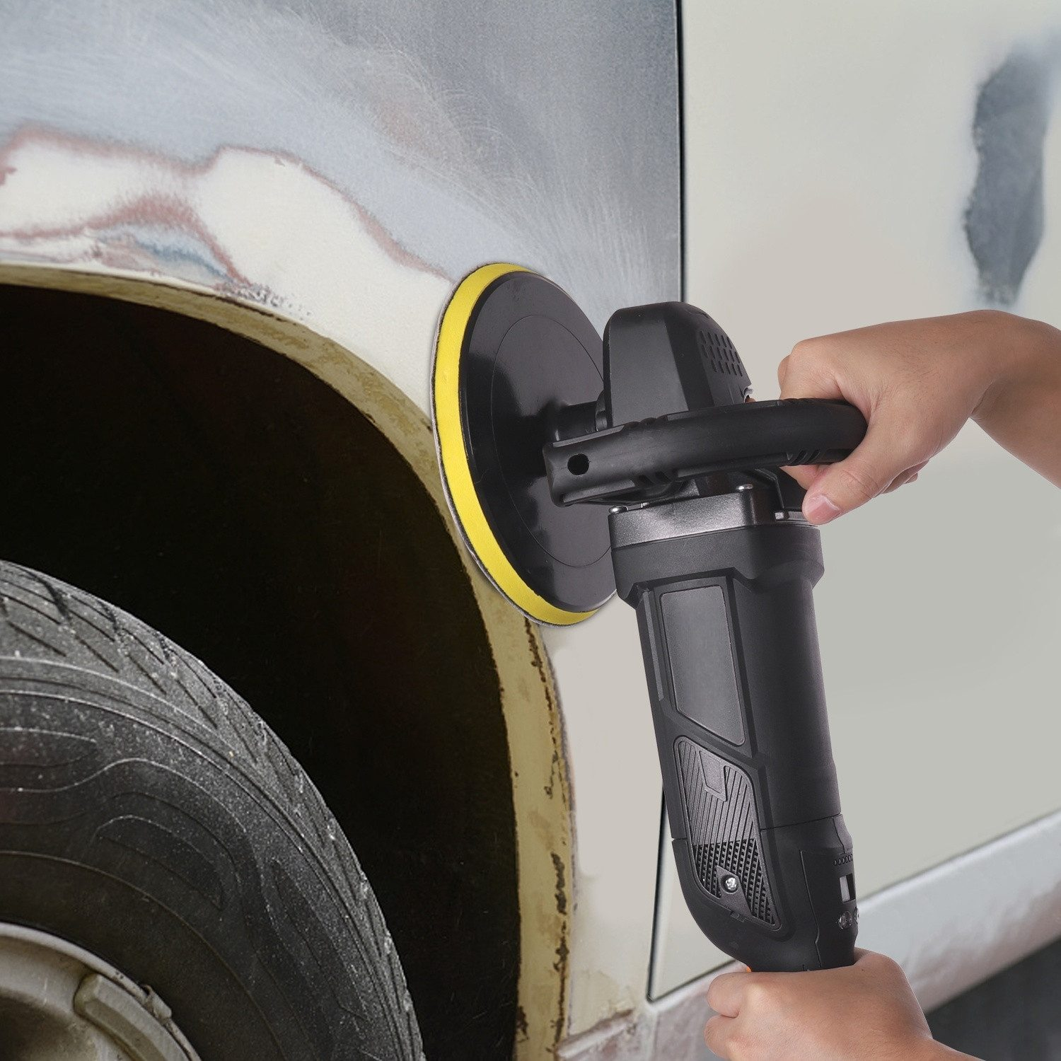 Eine Hand hält einen schwarzen Polierer, der auf ein Auto angewendet wird.