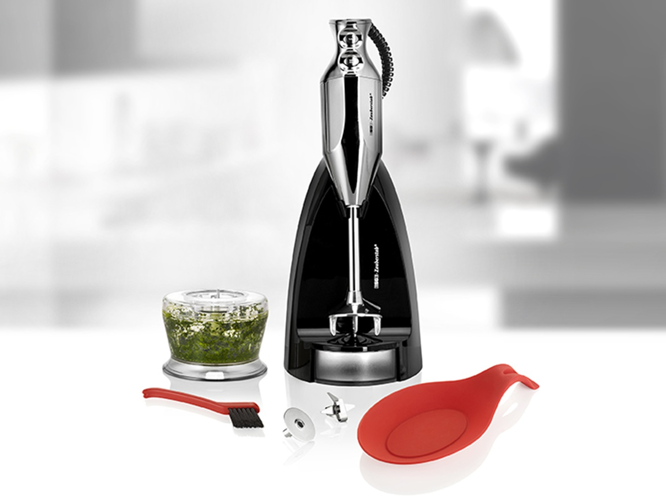 Ein schwarzer Stabmixer mit Zubehör: Mörser, Bürste, Klinge und Löffelablage.