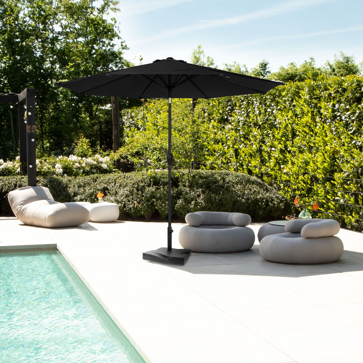 Outdoor furniture by pool: black umbrella, lounge chairs, side table.
