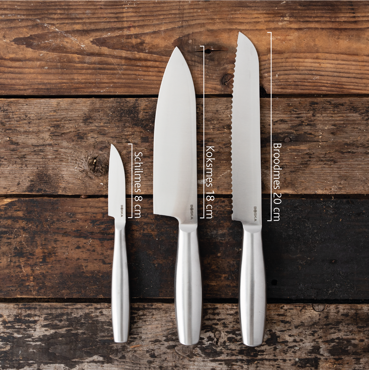Three stainless steel knives of varying blade lengths on a wooden background.