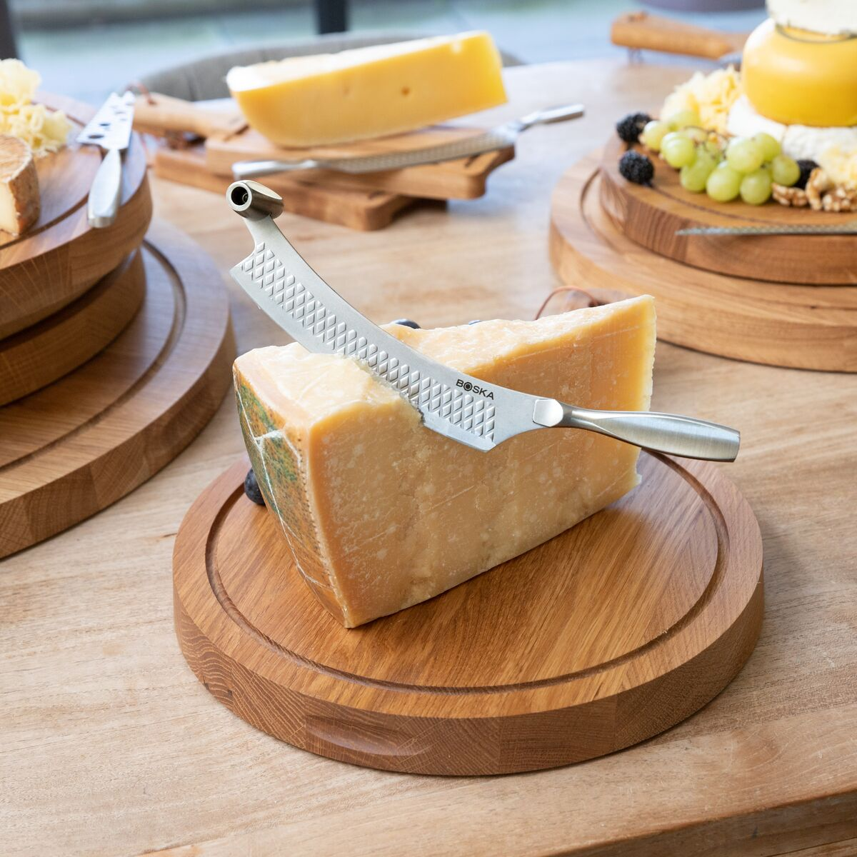 A piece of cheese with a knife on it, on a wooden board.