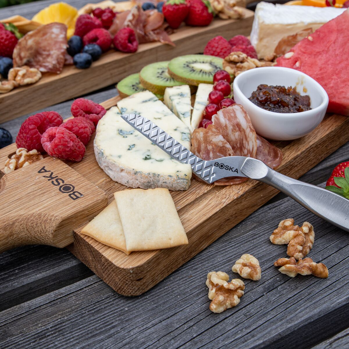 A wooden charcuterie board with cheese, fruits, meats, and nuts.