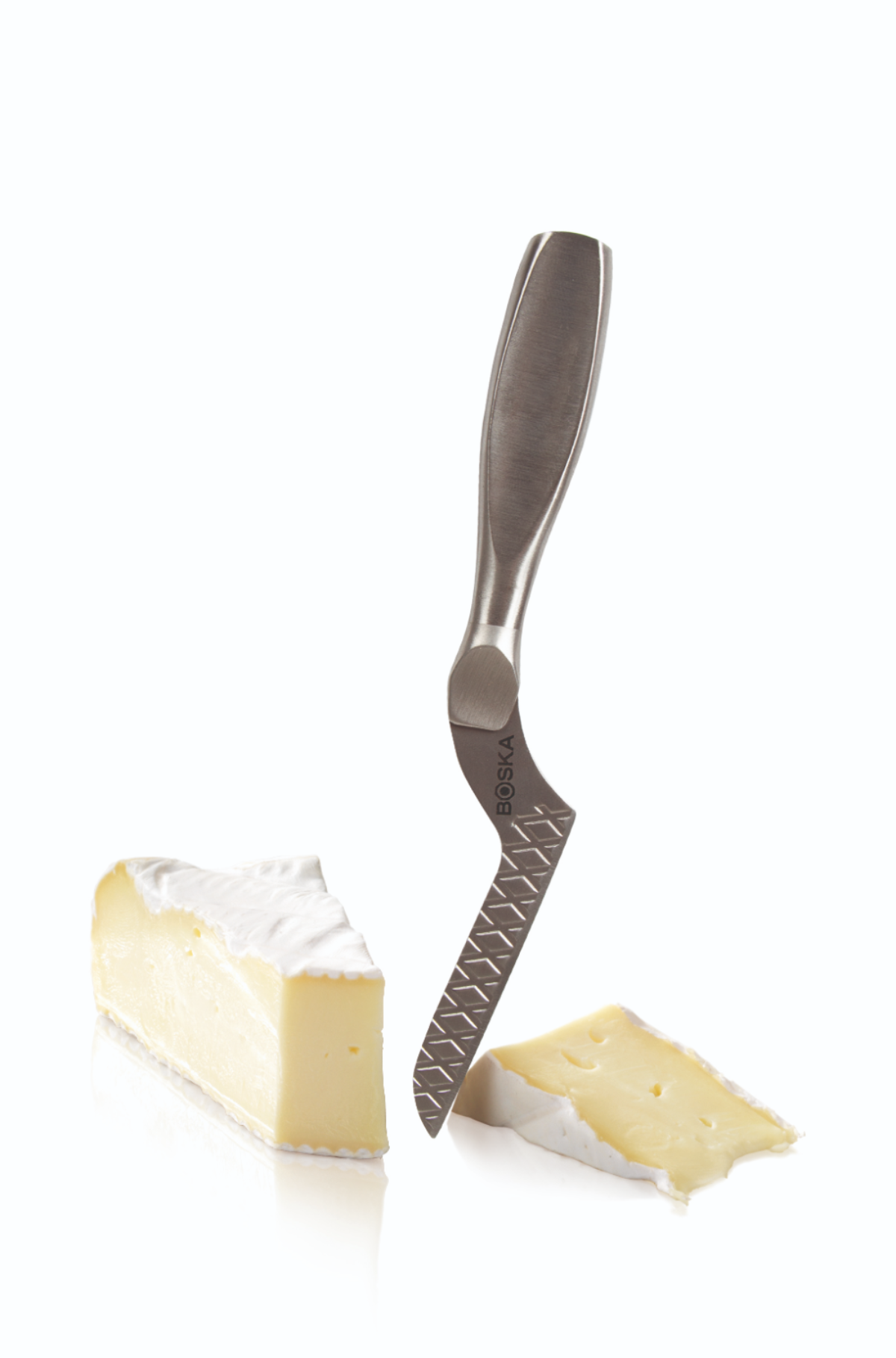 A cheese knife with a silver handle next to two pieces of brie cheese on a white background.
