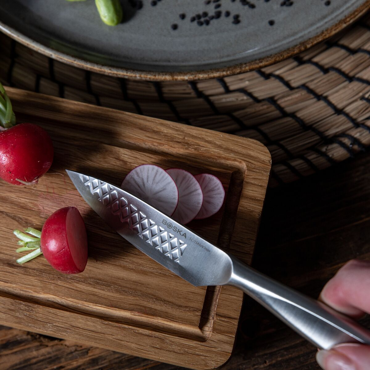 A knife with a pattern on a wooden board with radishes and slices.