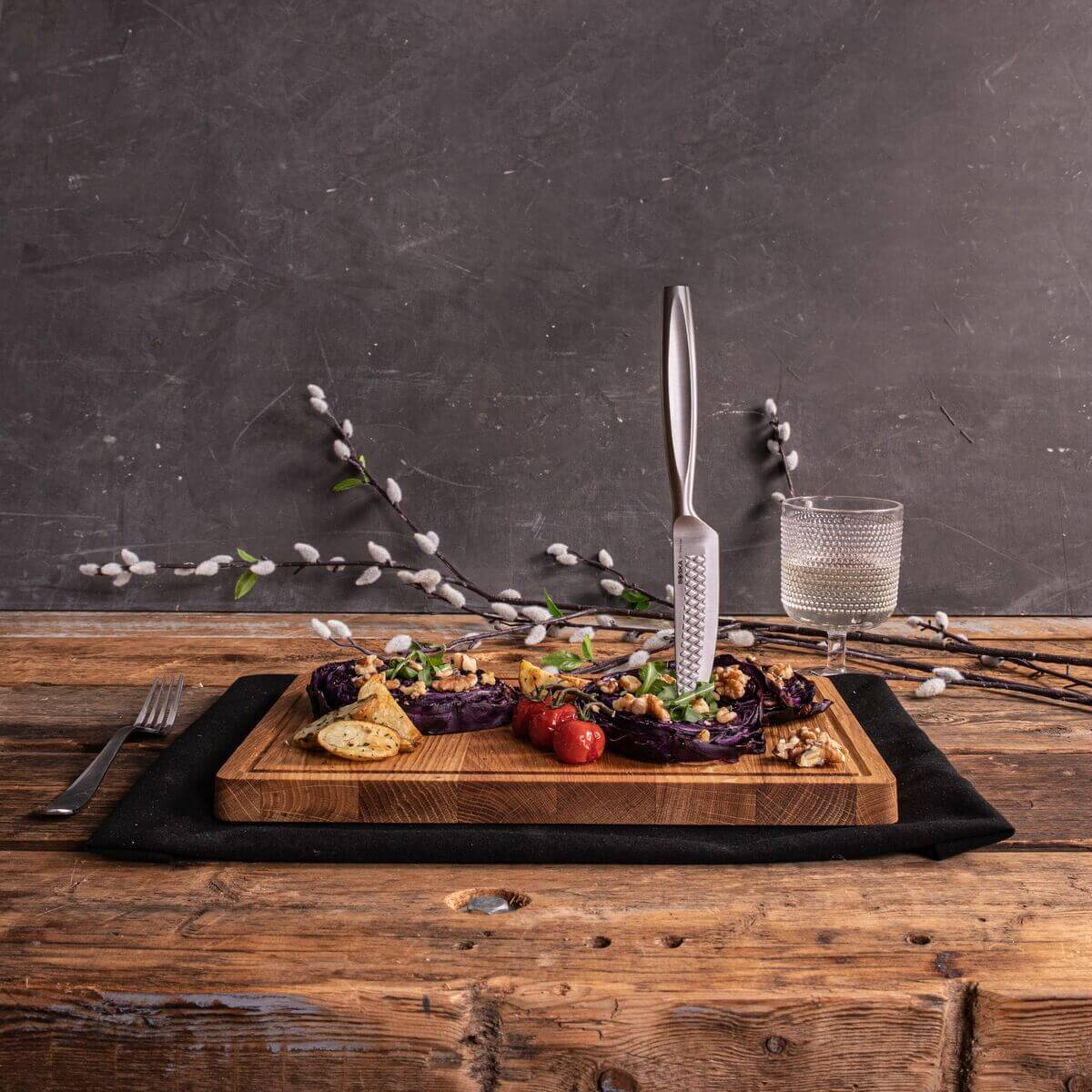 Stuffed red cabbage with nuts and tomatoes on a wooden board with a knife and wine.