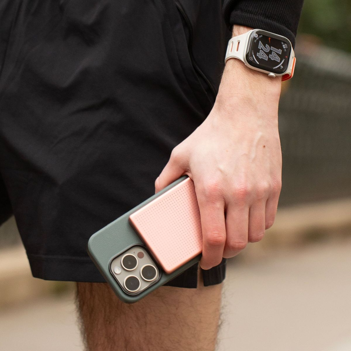 Una persona tiene un telefono con impugnatura rosa e indossa uno smartwatch al polso.