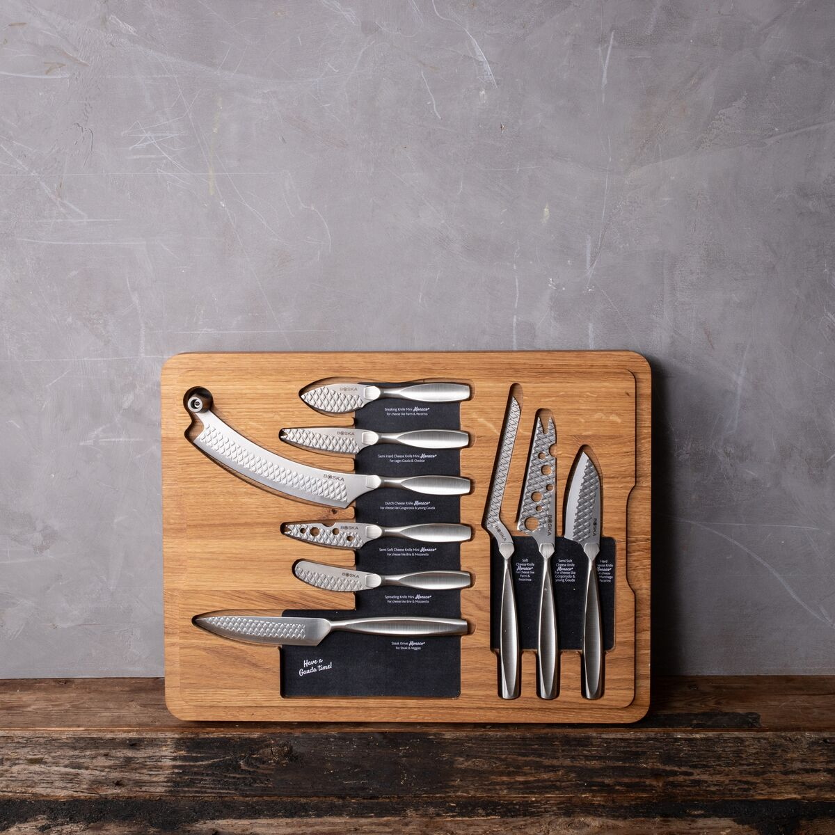 A wooden board with various cheese knives and a slicer.