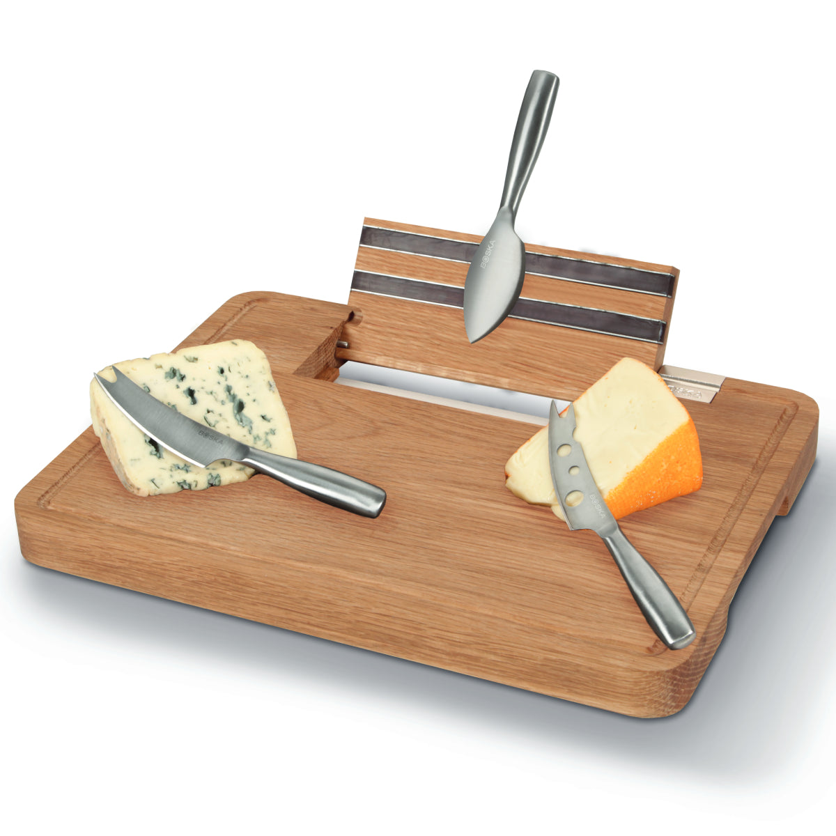 A wooden board with cheese and knives. A blue cheese and a hard cheese.
