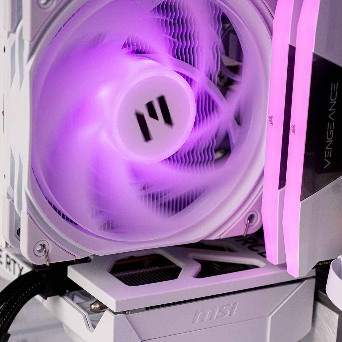 A white computer fan with purple lighting spins. RAM sticks are beside it.