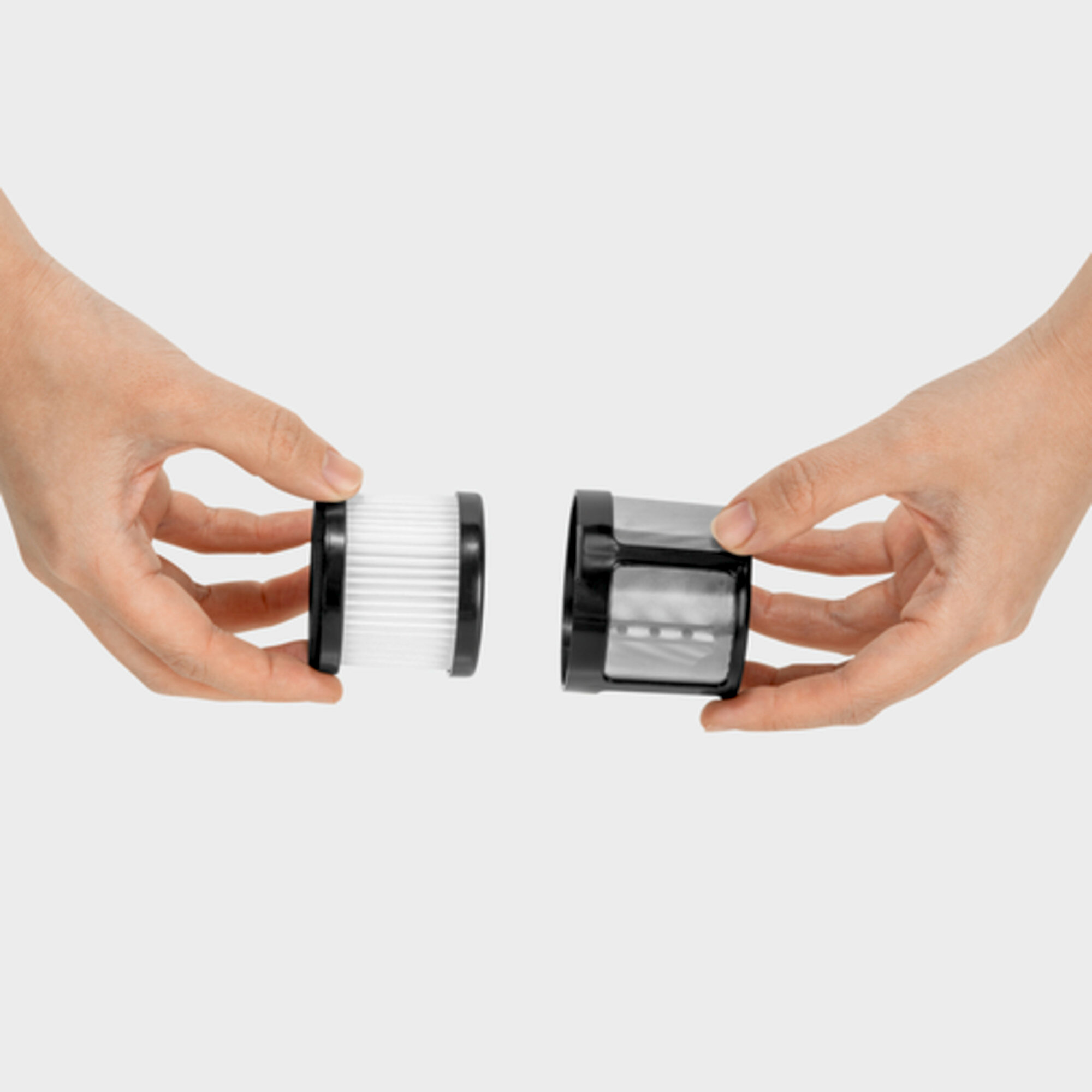 Two hands hold a white filter and a black filter housing. Clean parts.
