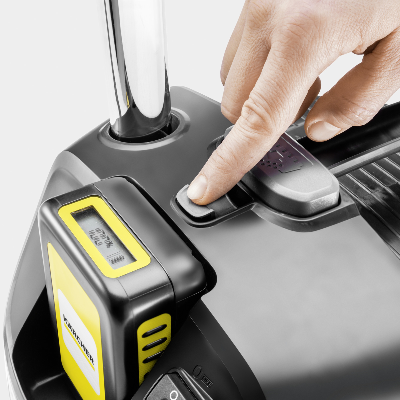 Une main appuie sur un bouton gris d'un appareil noir avec batterie jaune.