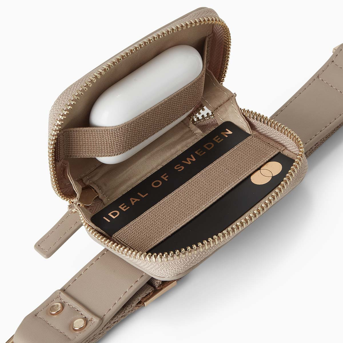 Eine beige Tasche mit einem weißen Kopfhörer-Etui und einer Karte mit der Aufschrift 'IDEAL OF SWEDEN'.