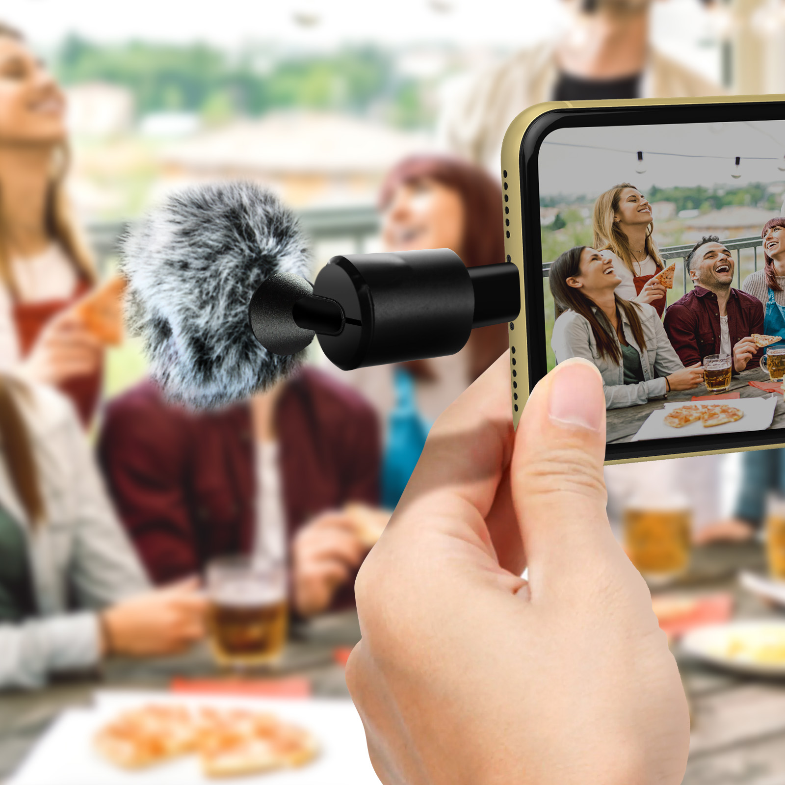 Mano tiene telefono con microfono, mostra gruppo che mangia pizza.