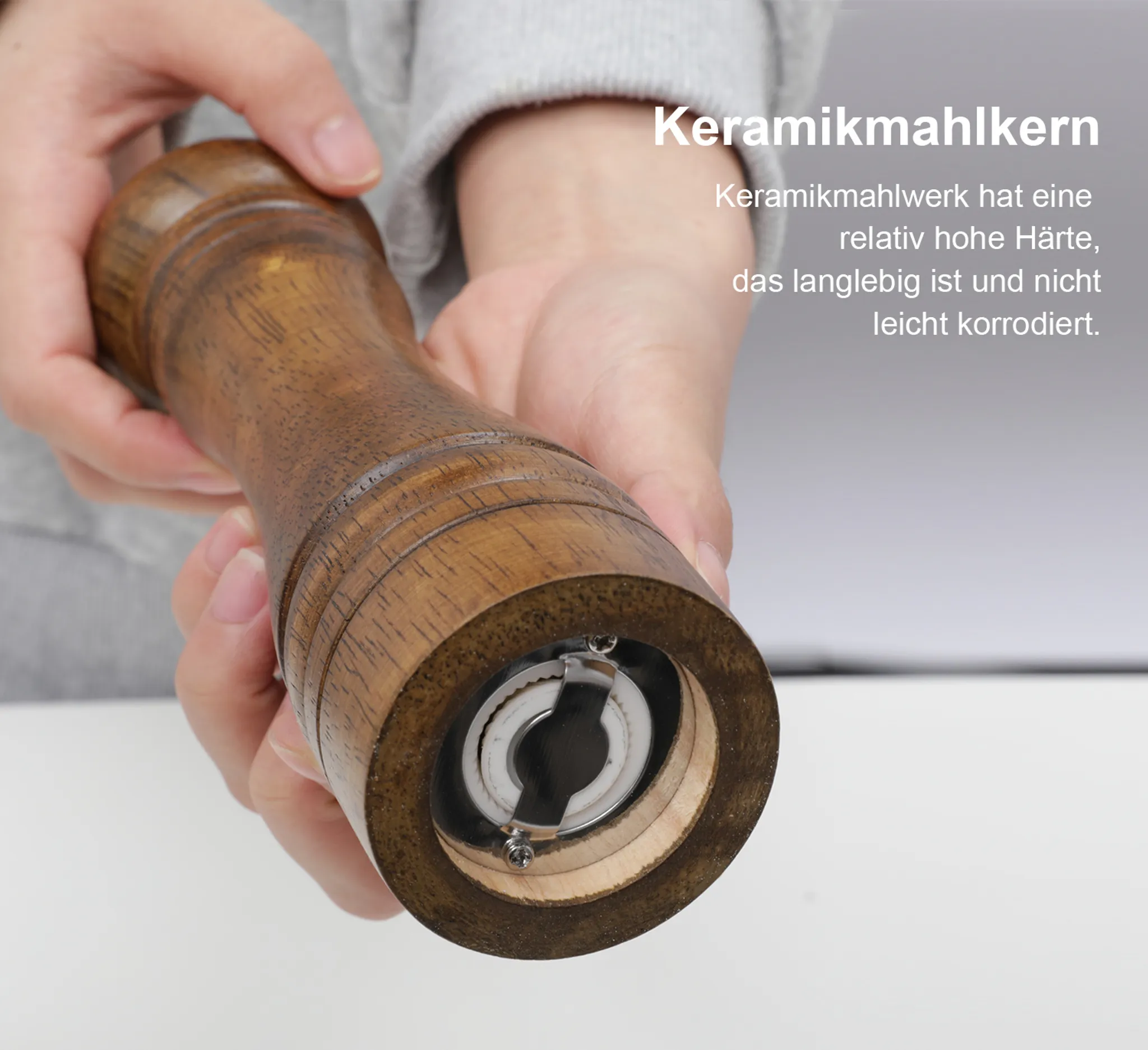 Holz-Gewürzmühle mit Keramikmahlwerk, von Händen gehalten.