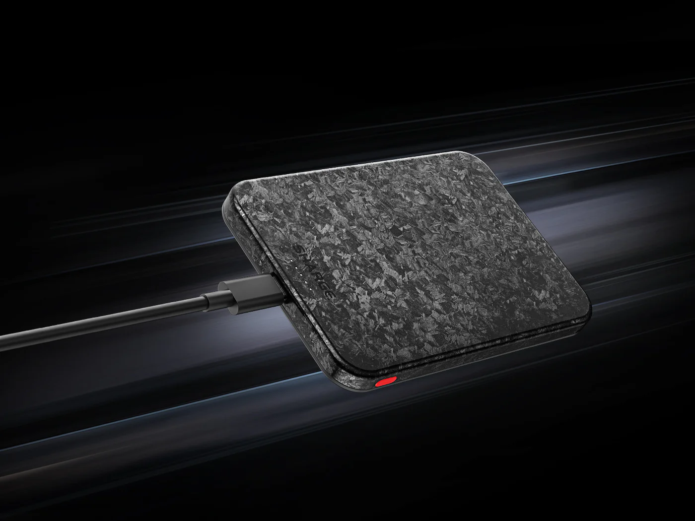 Chargeur noir à motif carbone, relié par câble, avec un voyant rouge allumé.