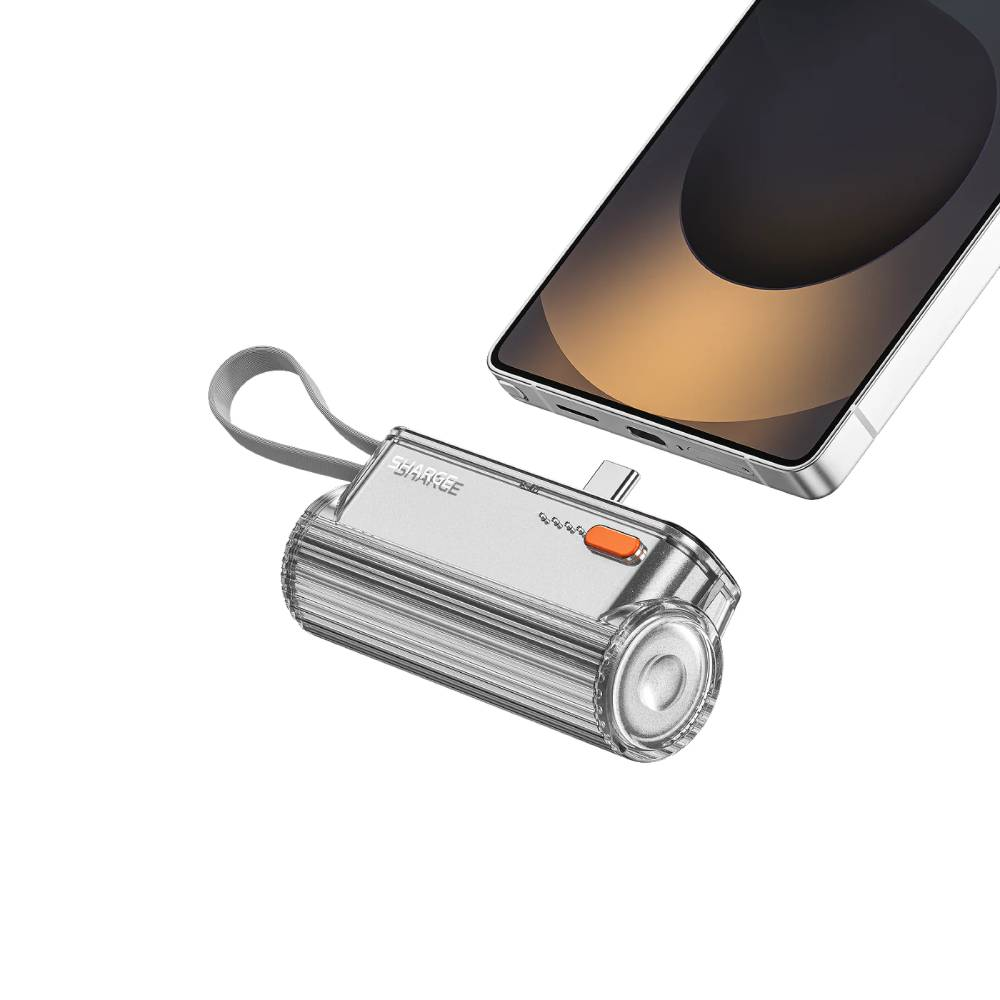 Un chargeur portable argenté avec USB-C et une lanière à côté d'un smartphone.