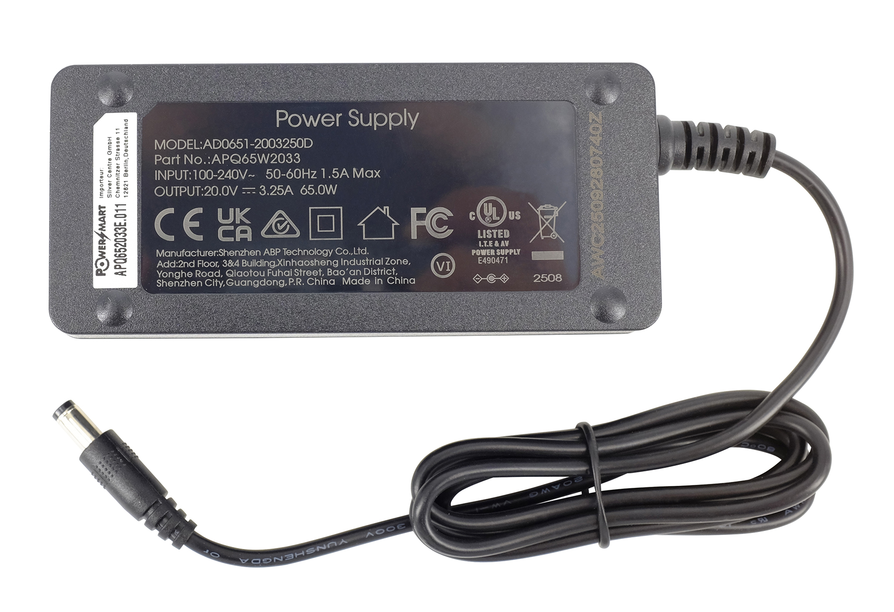 Grauer Netzteil mit schwarzen Kabeln und Stecker. Details auf dem Etikett.
