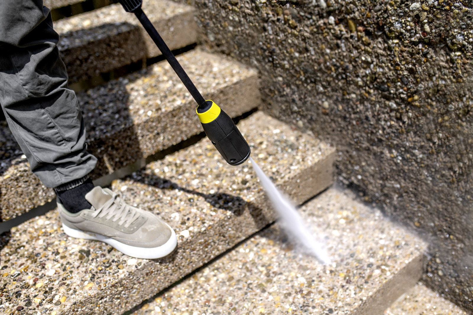 Osoba czyści kamienne stopnie myjką ciśnieniową.