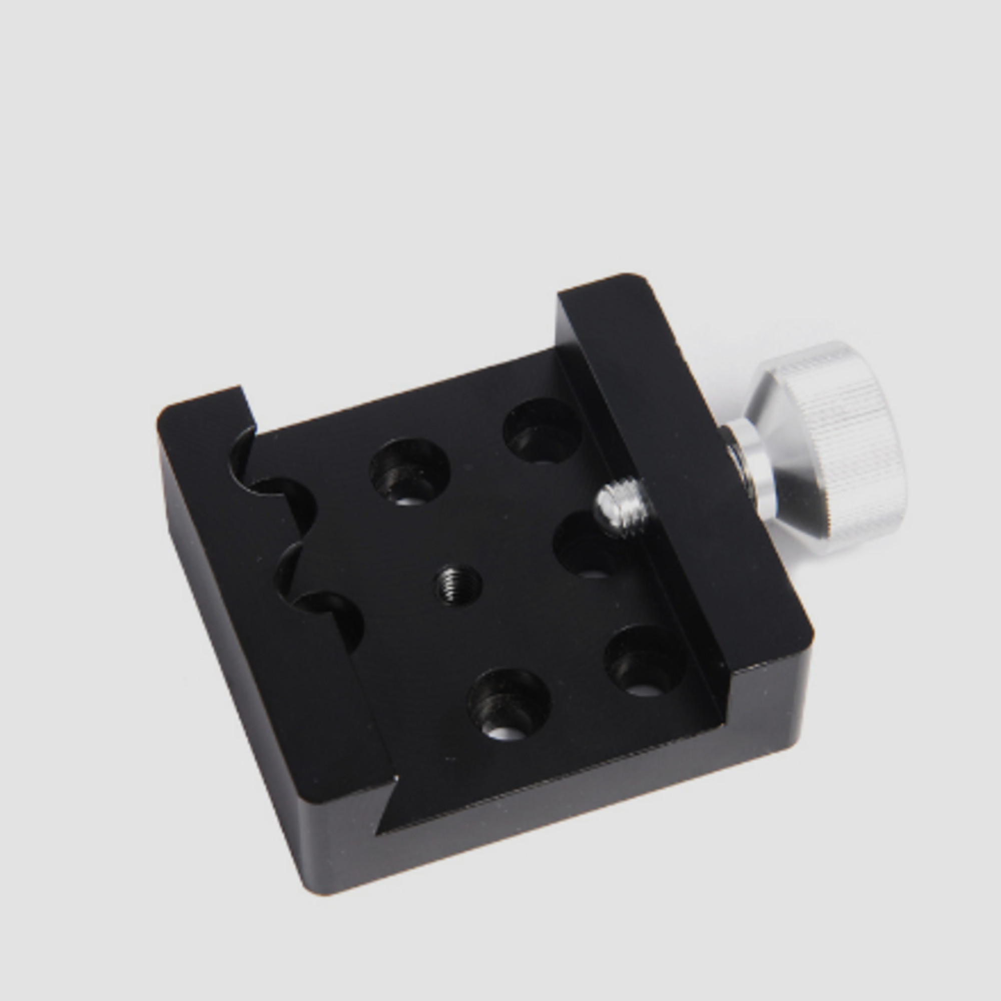 Ein schwarzer Klemmblock mit Rändelschraube und Gewindelöchern.