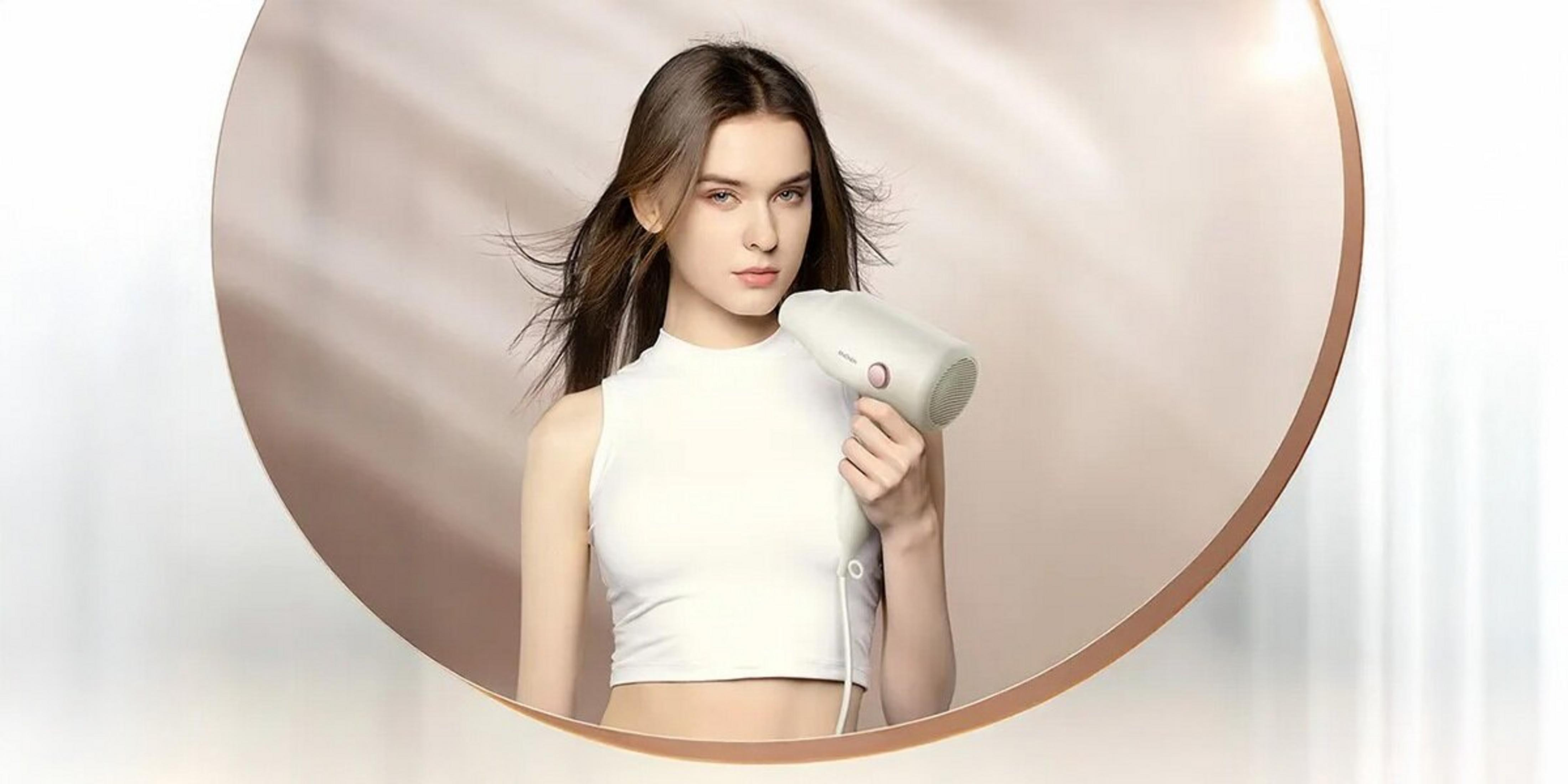 Una donna tiene un asciugacapelli bianco in una composizione circolare.