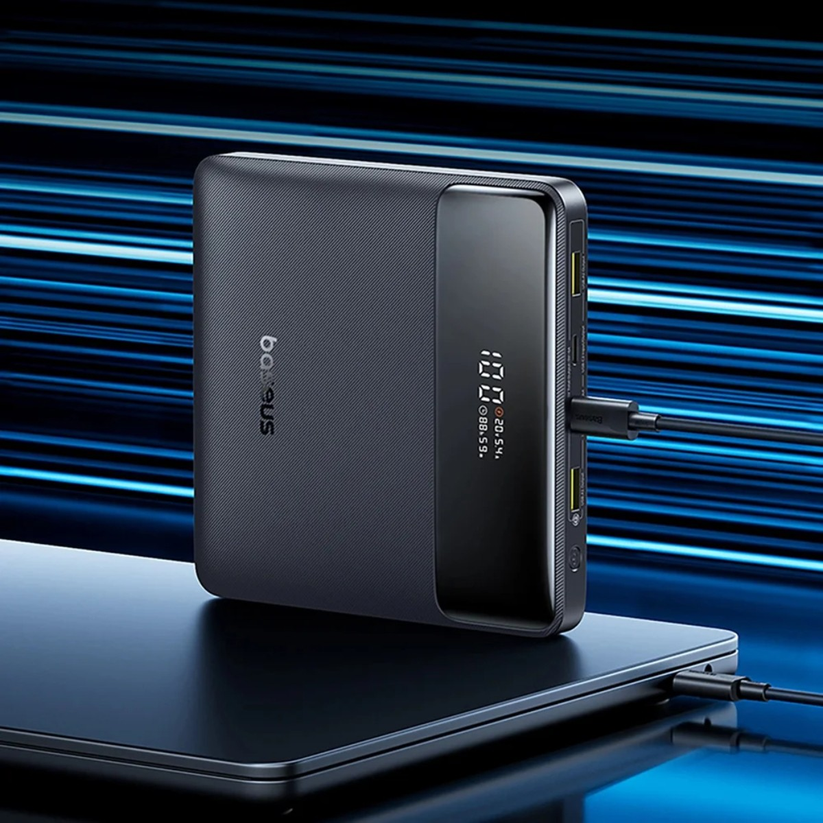 Zwarte powerbank met digitaal display, aangesloten op kabels.