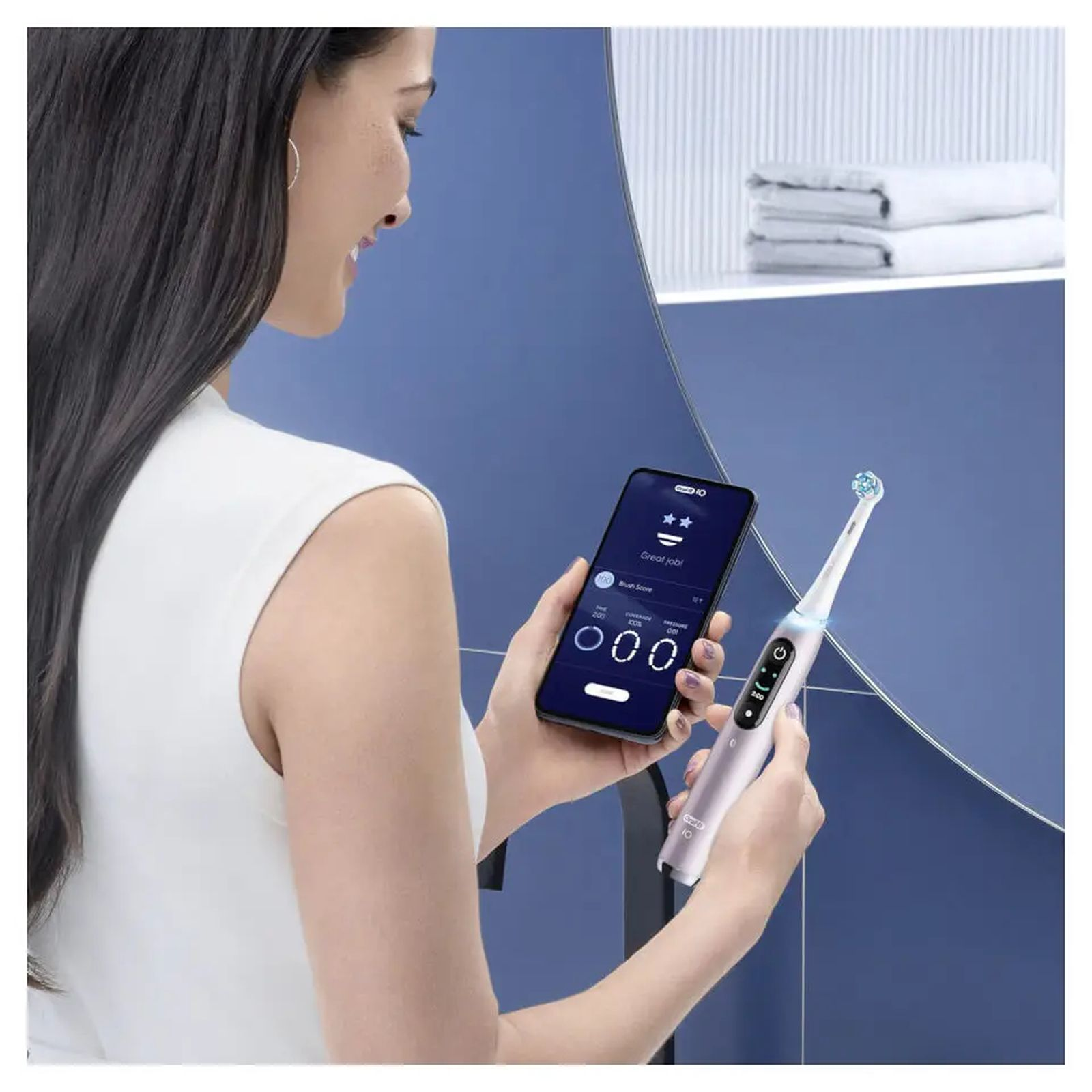 Kobieta trzymająca szczoteczkę elektryczną i smartfon z aplikacją.