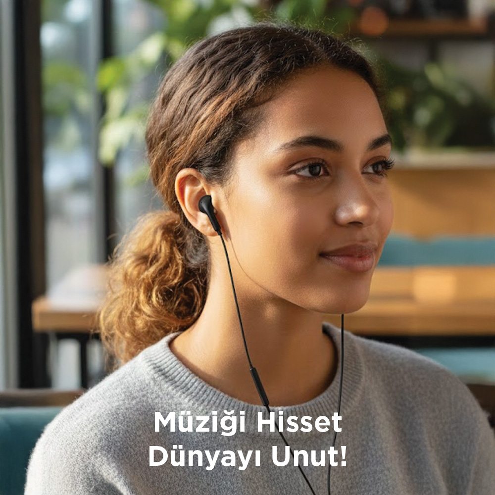Kulaklıklı genç kadın sağa bakıyor. Gri kazak giyiyor.