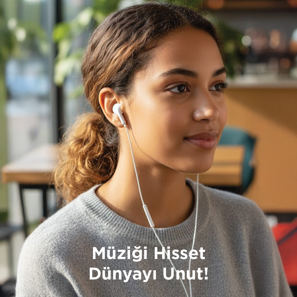 Kulaklık takan genç kadın, müzik dinliyor. Gri bir kazak giyiyor.