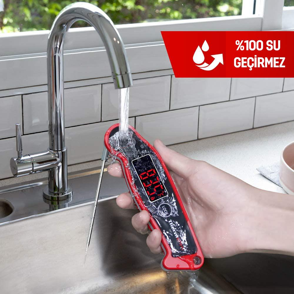 Sonda rossa digitale per carne tenuta sotto acqua corrente.