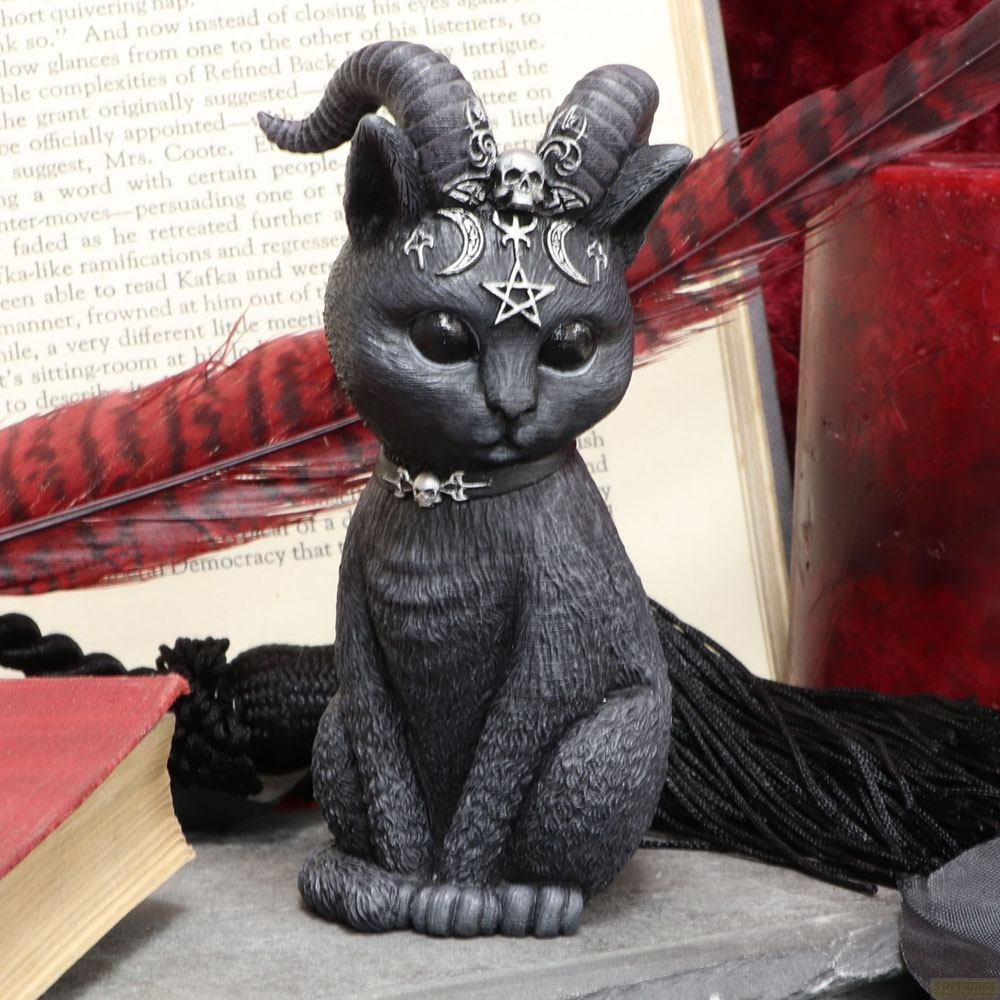 Eine schwarze Katze mit Hörnern, Totenköpfen und Pentagramm auf einem Buch.