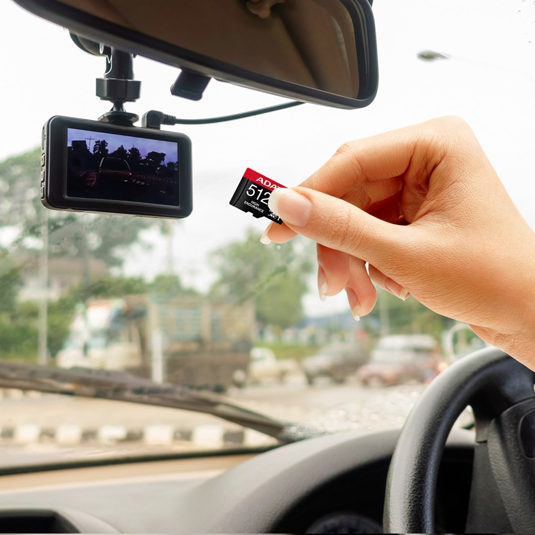 Dłoń trzyma kartę pamięci 512 GB przed samochodową kamerą.