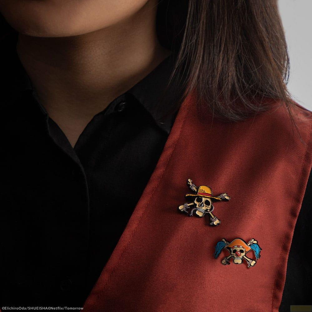 Zwei Totenkopf-Pins mit gekreuzten Knochen auf dunkelrotem Stoff.