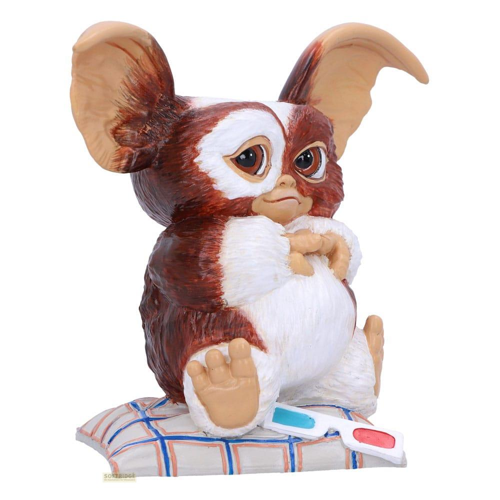 Eine braun-weiße Gremlin-Figur sitzt auf einem karierten Kissen mit 3D-Brille.
