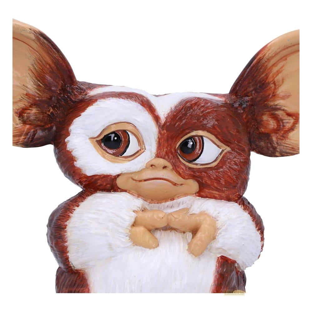 Ein braun-weißer Gremlin mit großen Ohren und Händen vor der Brust.