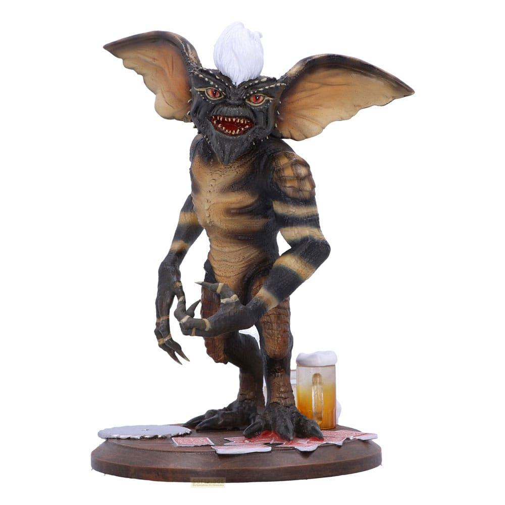 Ein Gremlin mit Streifen und weißen Haaren sitzt neben einem Bierglas.