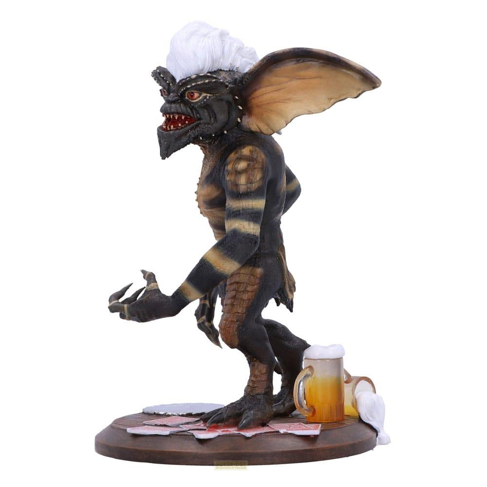 Eine Gremlin-Figur mit weißem Haar steht auf Karten und neben einem Bierkrug.