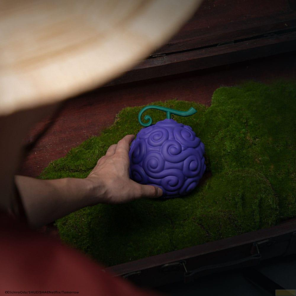 Eine Hand greift nach einer lilafarbenen, spiralförmigen Teufelsfrucht auf Moos.