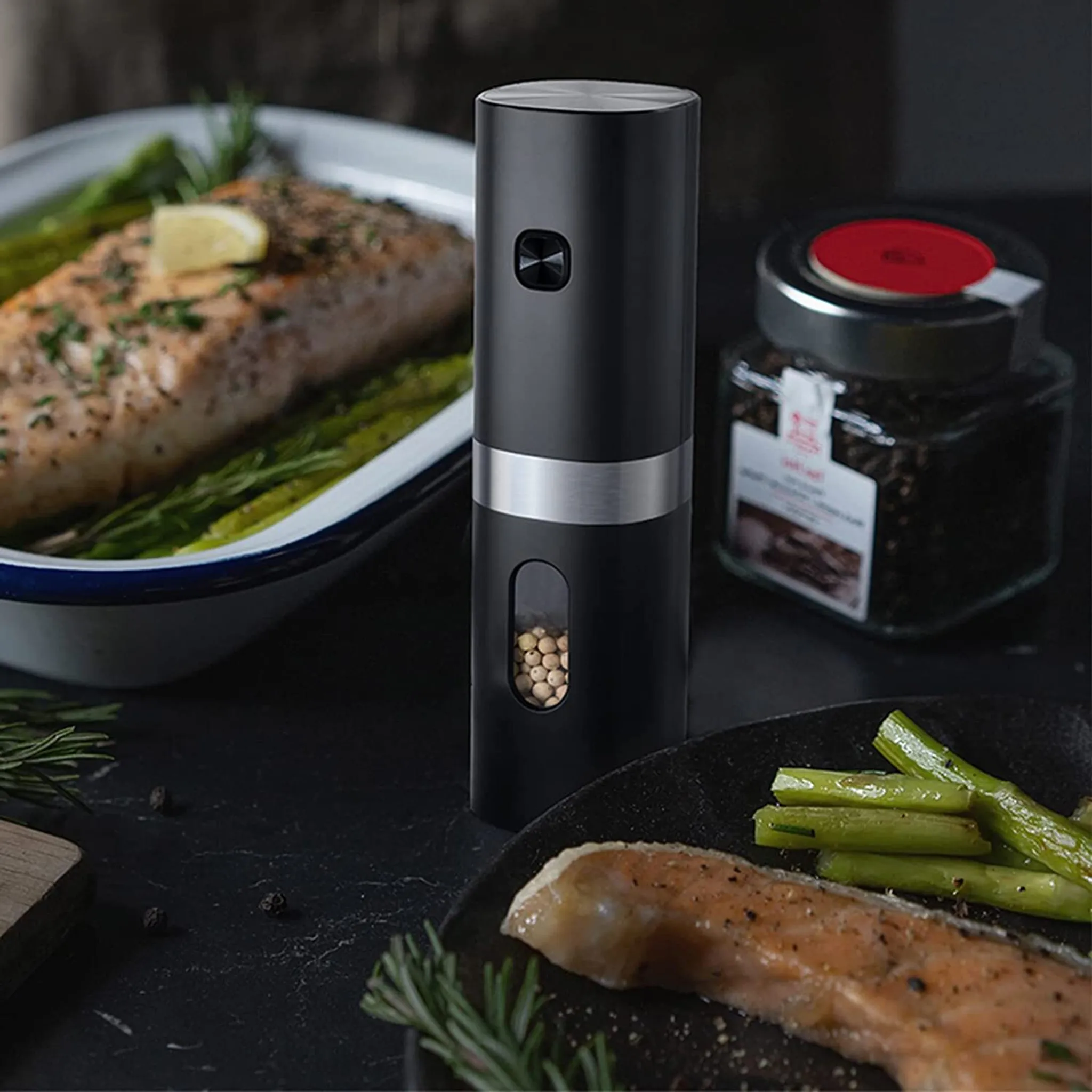 Elektrische Pfeffermühle neben Lachs mit Spargel und einem Glas Pfefferkörnern.
