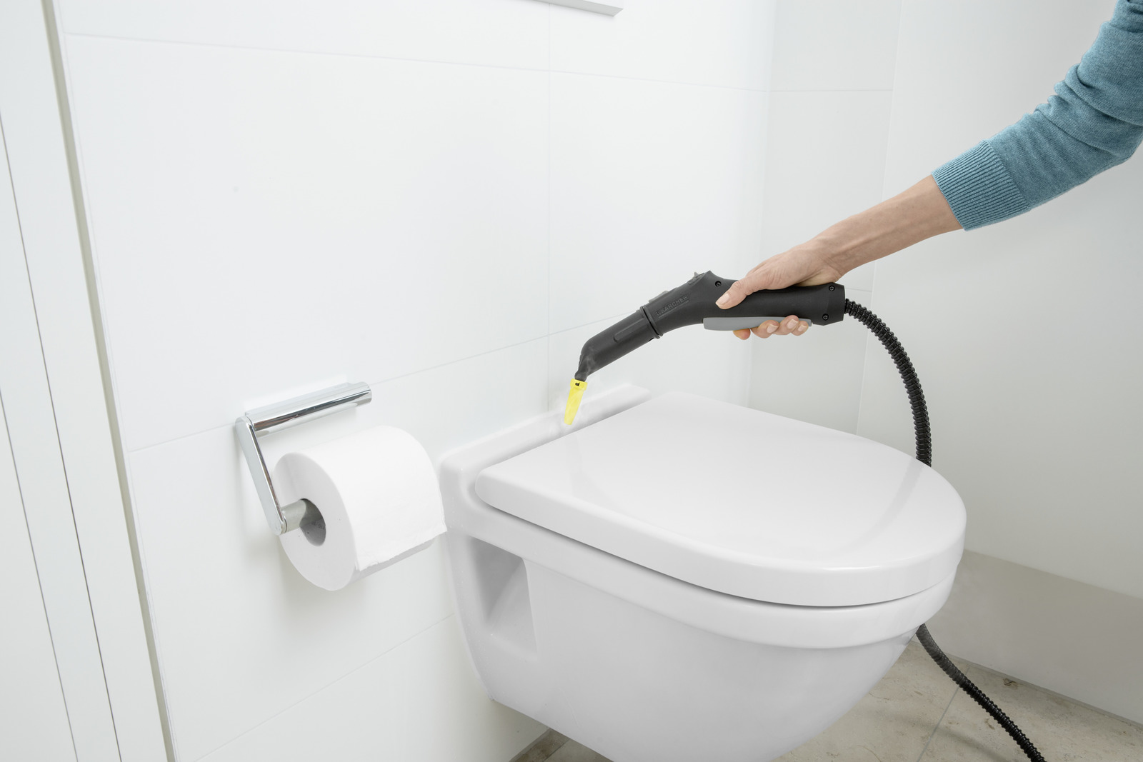Parownica dezynfekuje muszlę klozetową. Obok uchwyt na papier toaletowy.