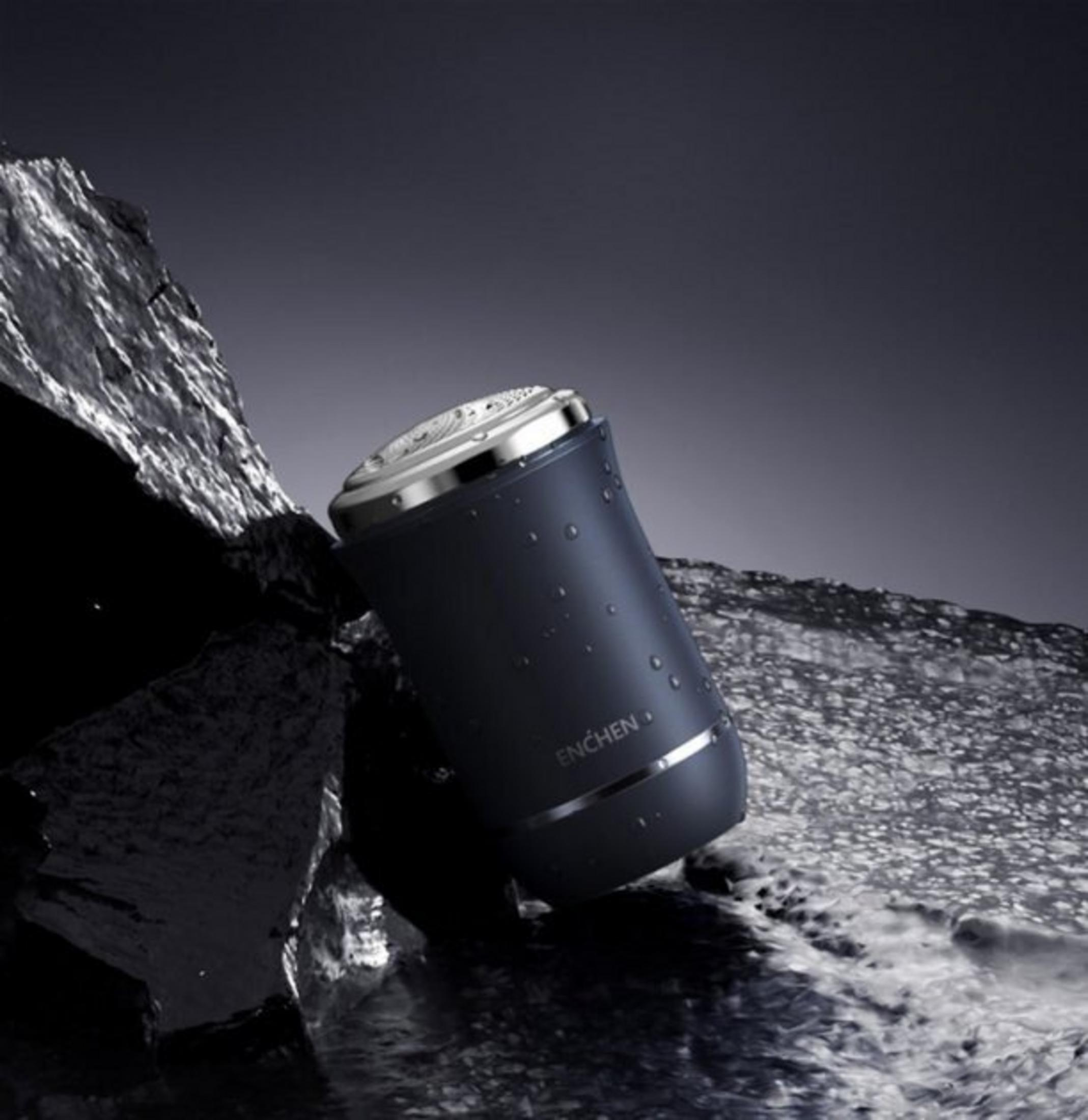Un rasoio scuro con gocce d'acqua riposa sulle rocce vicino all'acqua.